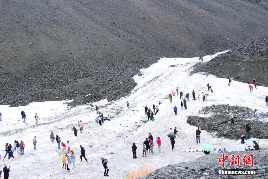 8月初，游客在独库公路边上体验滑雪。